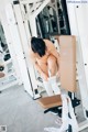 A naked woman is sitting on a bench in a gym.