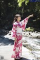 A woman in a pink and white kimono standing by a river.