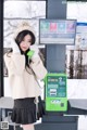 A woman in a white sweater and black skirt talking on a green phone.