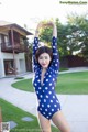 A woman in a blue and white polka dot swimsuit posing for a picture.