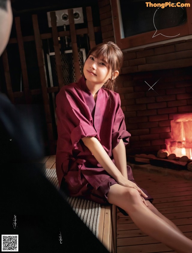 A woman sitting on a wooden bench in front of a fireplace.