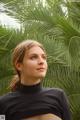 A woman in a black top standing in front of a palm tree.